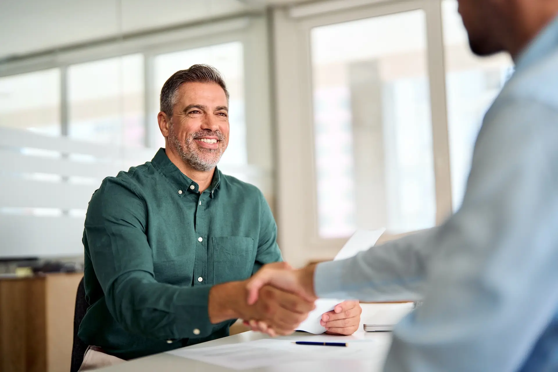 smiling man shaking hands with another man in a meeting room